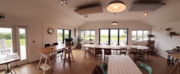 Image shows the cafe space at the refectory, with lots of light through the windows and an array of tables.